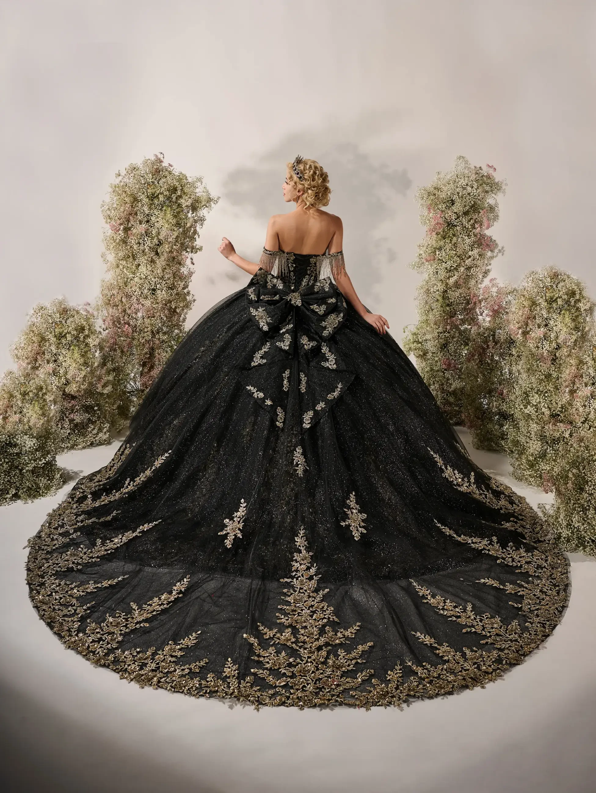 model is wearing a strapless black and gold quinceanera dress