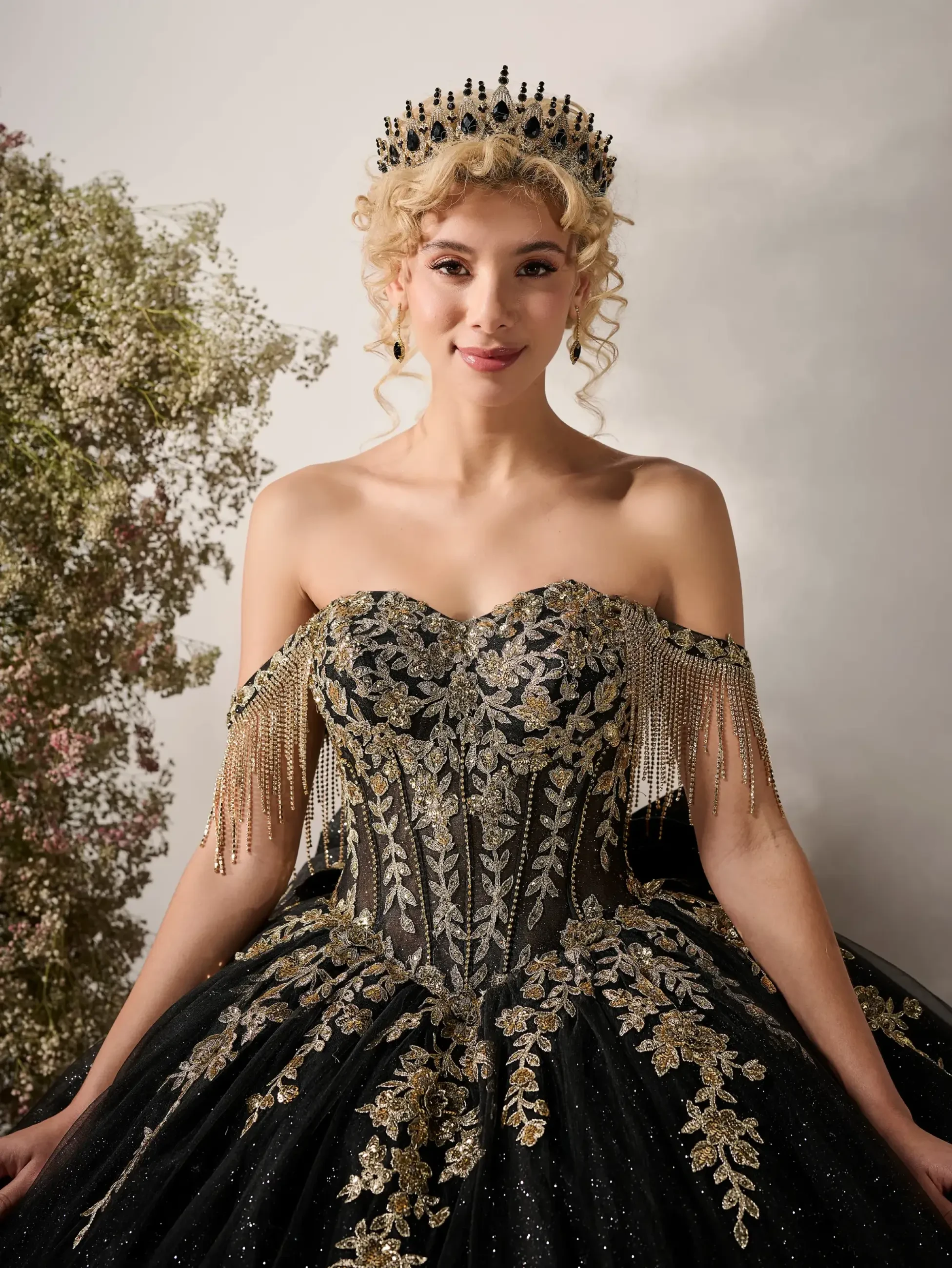 model is wearing a strapless black and gold quinceanera dress