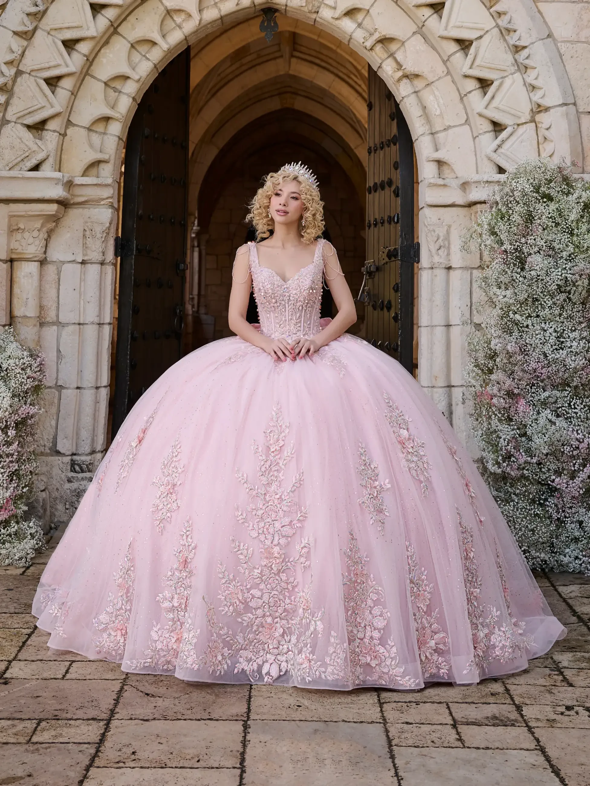 model is wearing a light pink sleeveless quinceanera dress