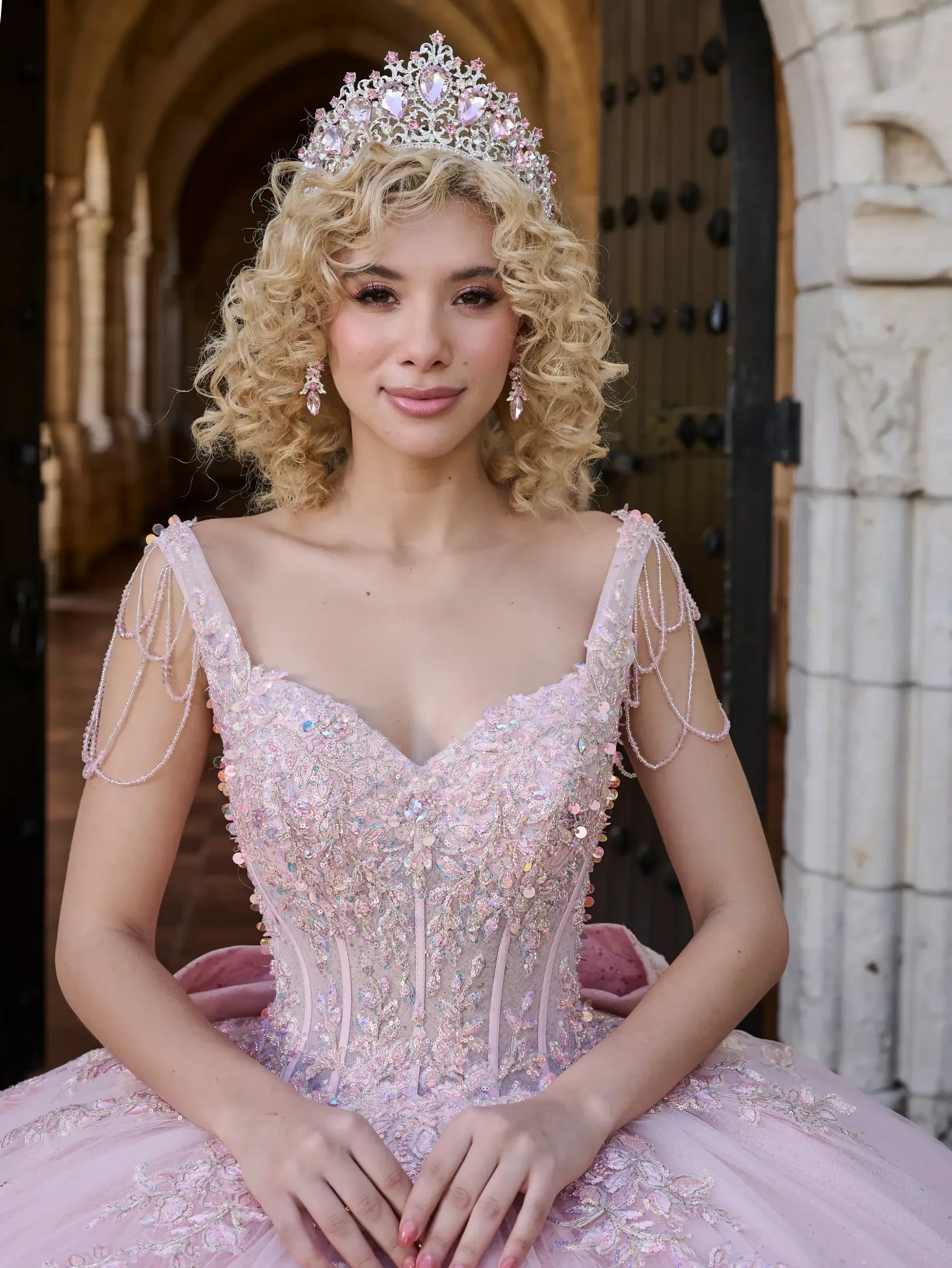 model is wearing a light pink sleeveless quinceanera dress