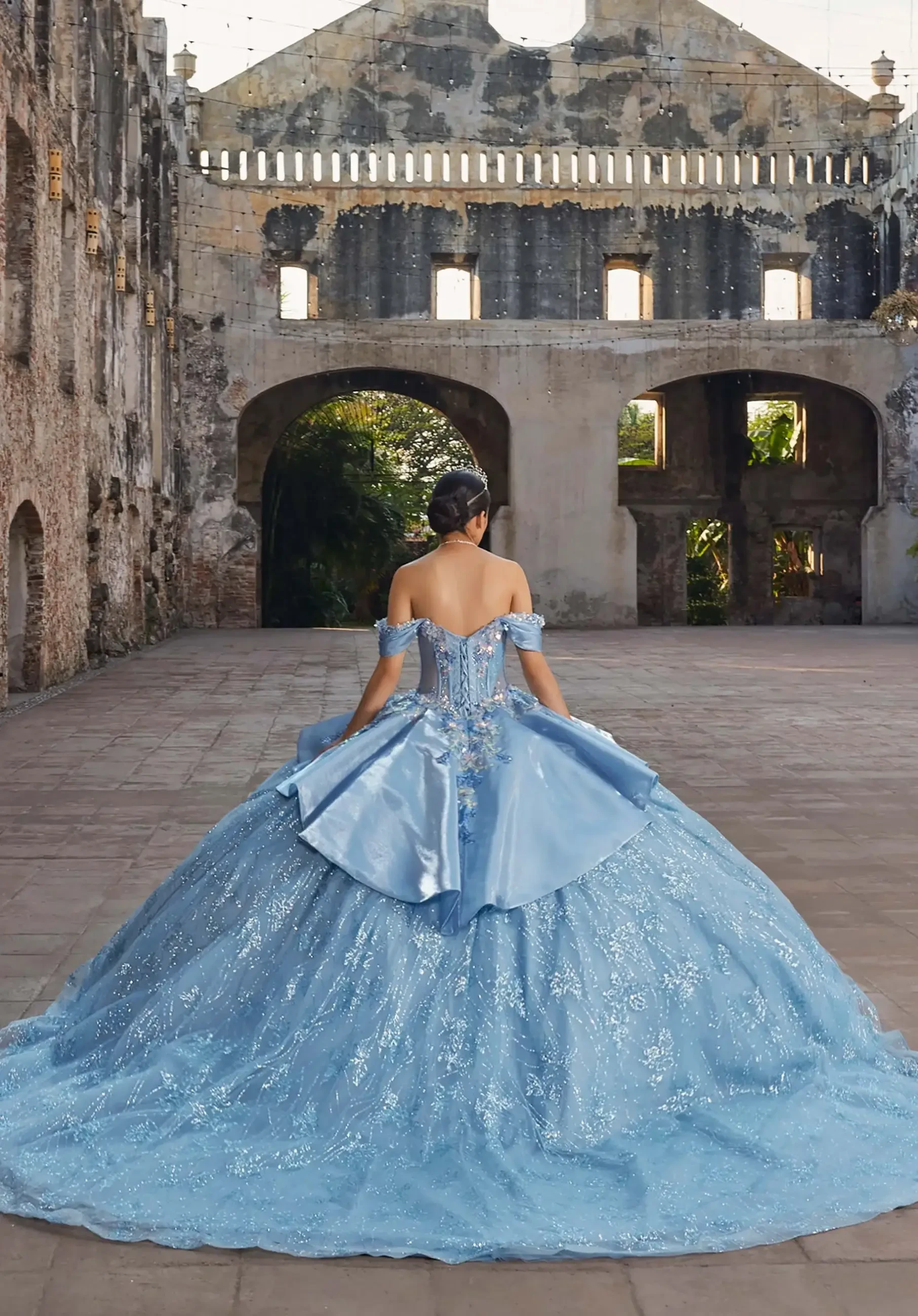 model is wearing a dusty blue quinceanera dress