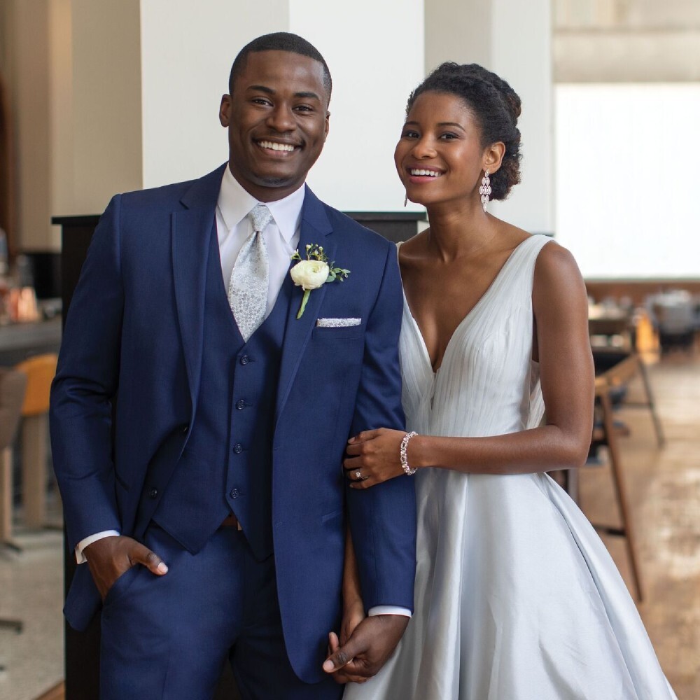 Сouple wearing a white gown and a blue suit. Mobile image